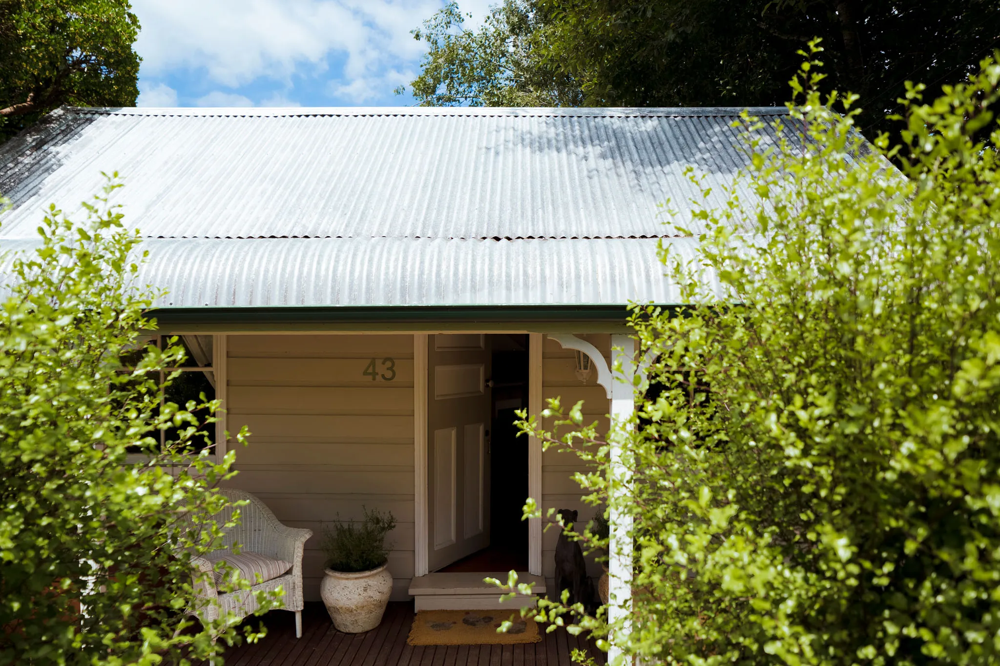 Front entrance of the cottage at number 43, framed by garden foliage